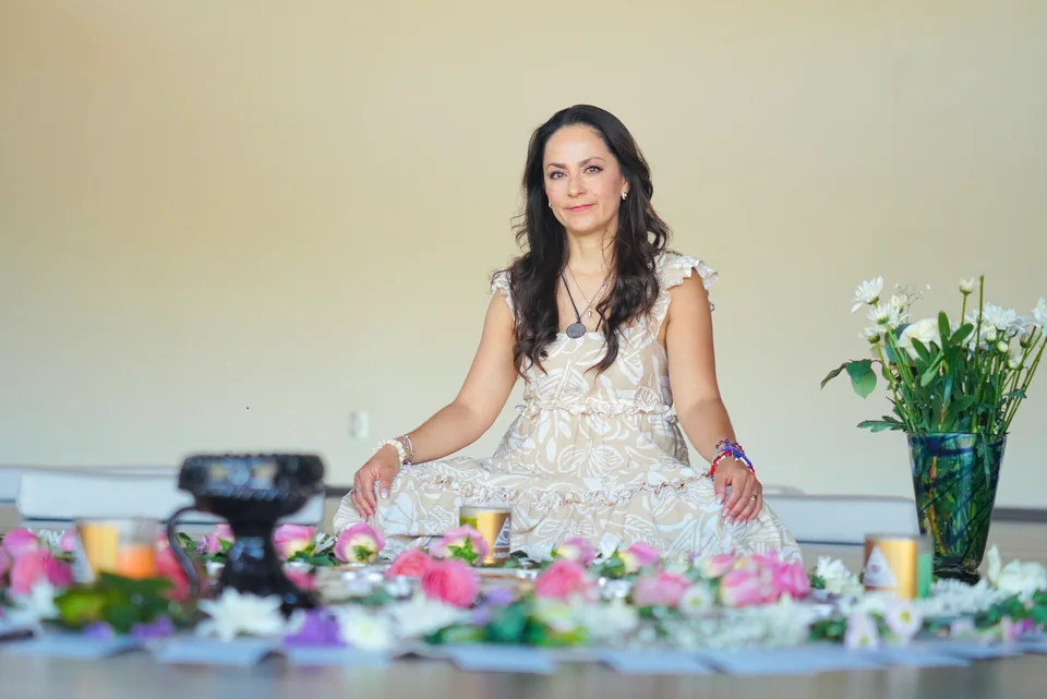 Moni sentada junto a flores y velas